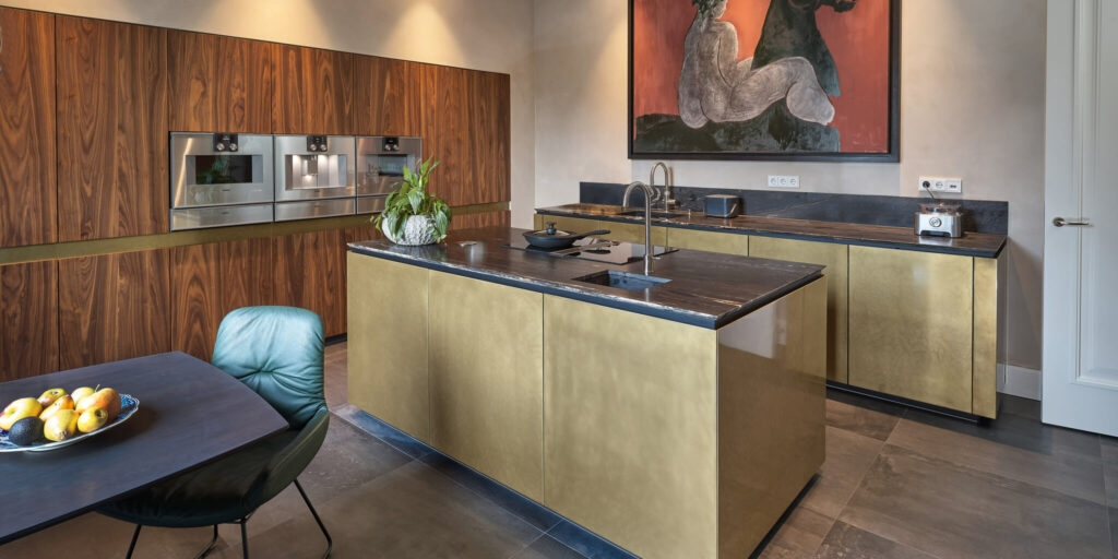 Luxe keuken van Tieleman Keukens met Mereno Milano front in messing en notenhout