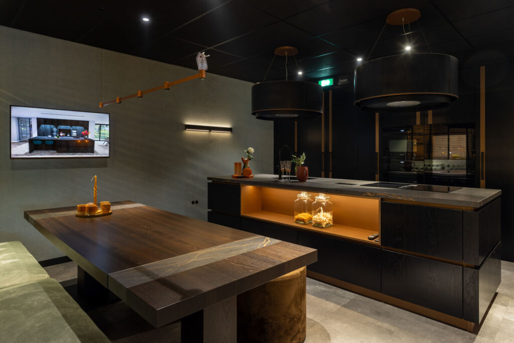 Showroom donkere keuken met groot eiland en maatwerk tafel Mennen Keukens + Interieurs
